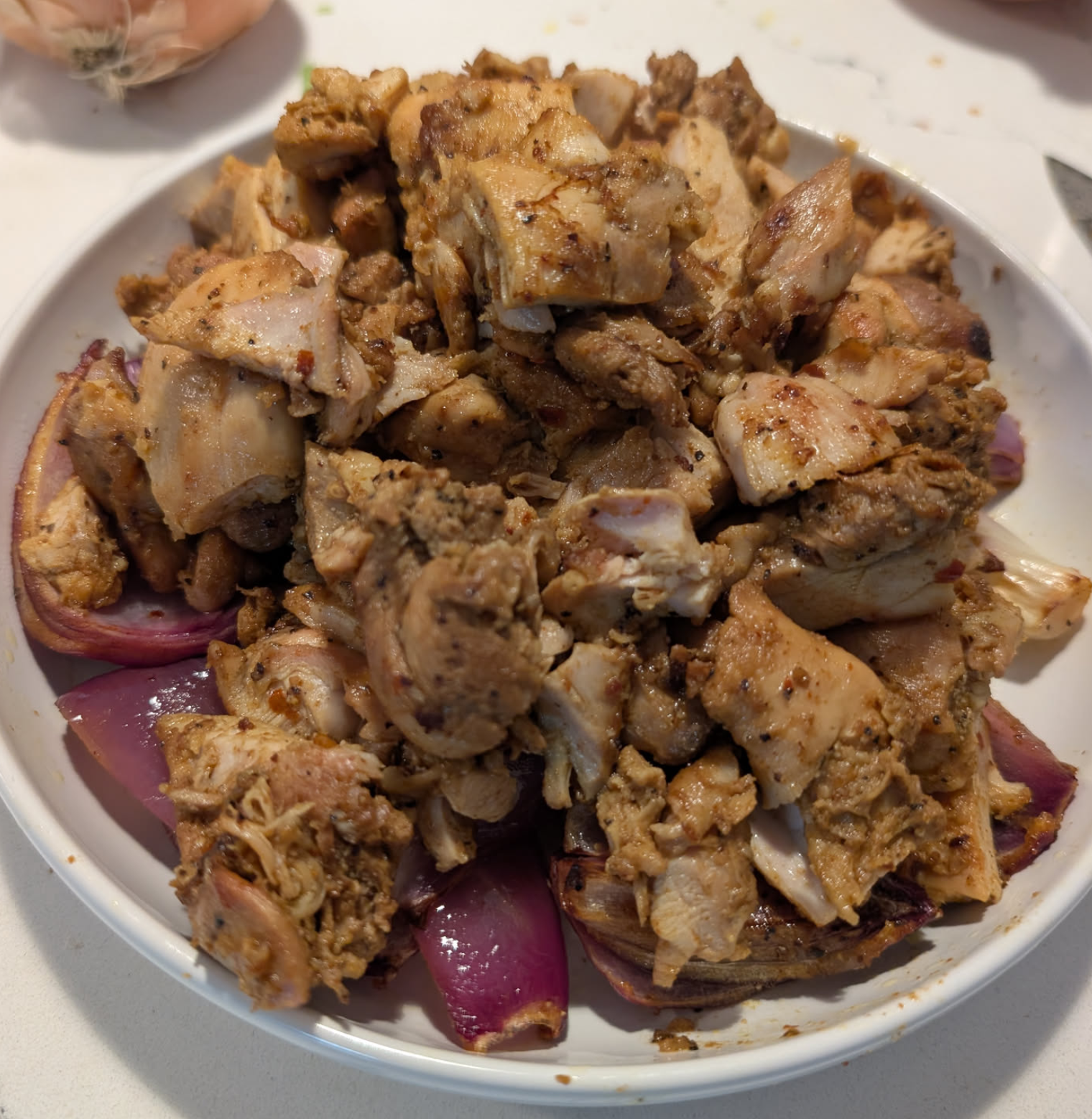 cooked chicken shawarma on a plate, red onions visible alongside the chicken